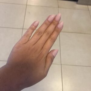 imagem com uma mão feminina mostrando as unhas pintadas em uma rosa claro