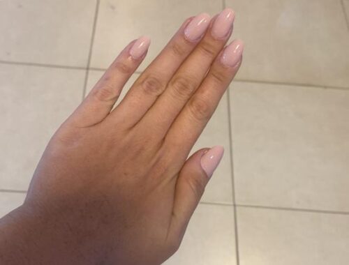 imagem com uma mão feminina mostrando as unhas pintadas em uma rosa claro